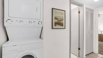 Een wasruimte met een wasmachine en droger, een inlijsting foto aan de muur, en een deur die naar een andere ruimte leidt.