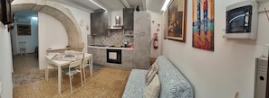 Eine kompakte Küche mit Essbereich, einer Couch und einem an der Wand befestigten Feuerlöscher.