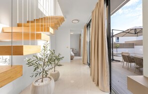 A modern interior with a wooden staircase, potted plants, and a view of an outdoor patio area. - Stunning home in Tribunj (Tribunj)