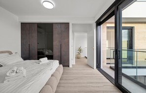 A modern bedroom with a large bed, a wardrobe, and a view to a balcony. - Stunning home in Tribunj (Tribunj)