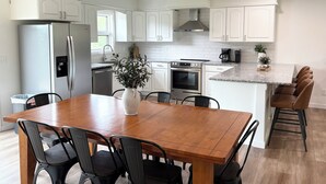 Una cocina moderna con armarios blancos, un refrigerador de acero inoxidable, horno integrado y una cafetera.