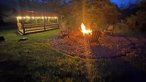 Un área de estar al aire libre con un brasero y una terraza con luces colgantes.