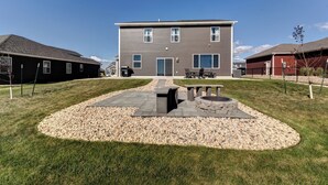 A two-story building with a patio area featuring a fire pit and seating. - Executive Stay for Work & Family (Rapid City)