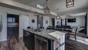 A modern kitchen with a central island, stainless steel appliances, and pendant lighting. - Executive Stay for Work & Family (Rapid City)