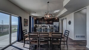 A modern kitchen with dark cabinetry, a central island, and pendant lighting. - Executive Stay for Work & Family (Rapid City)