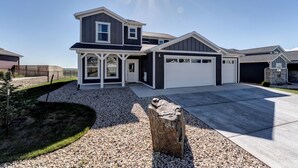 A modern two-story house with a garage, a driveway, and a well-maintained lawn. - Executive Stay for Work & Family (Rapid City)