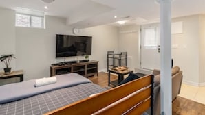 Quarto com cama, televisão, escrivaninha e cadeira.