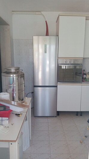 Eine kompakte Küche mit einem Edelstahl-Kühlschrank, einem eingebauten Backofen und einer kleinen Arbeitsfläche.