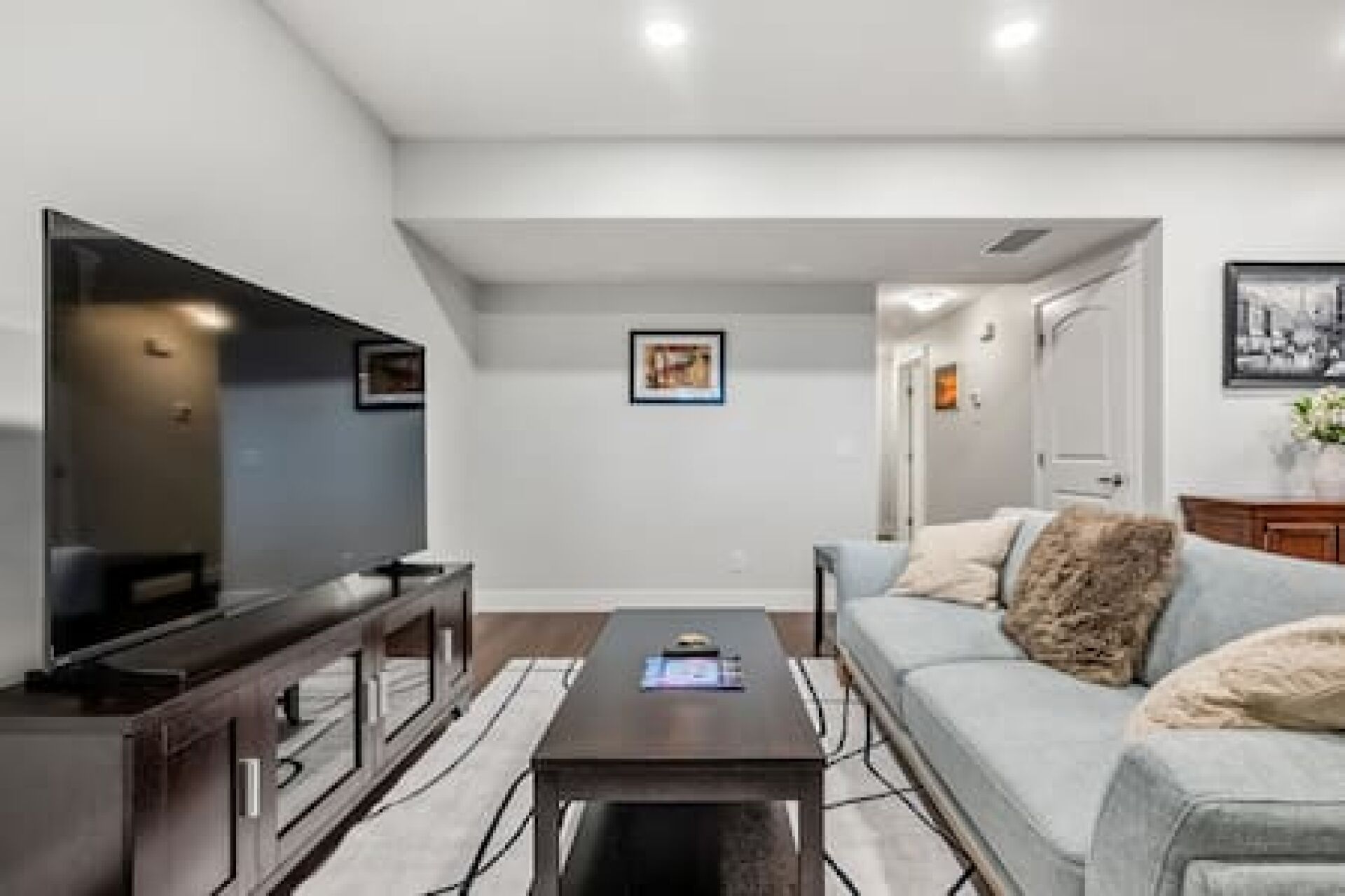 A living room with a flat-screen TV, a coffee table, a sofa, and a framed picture on the wall.