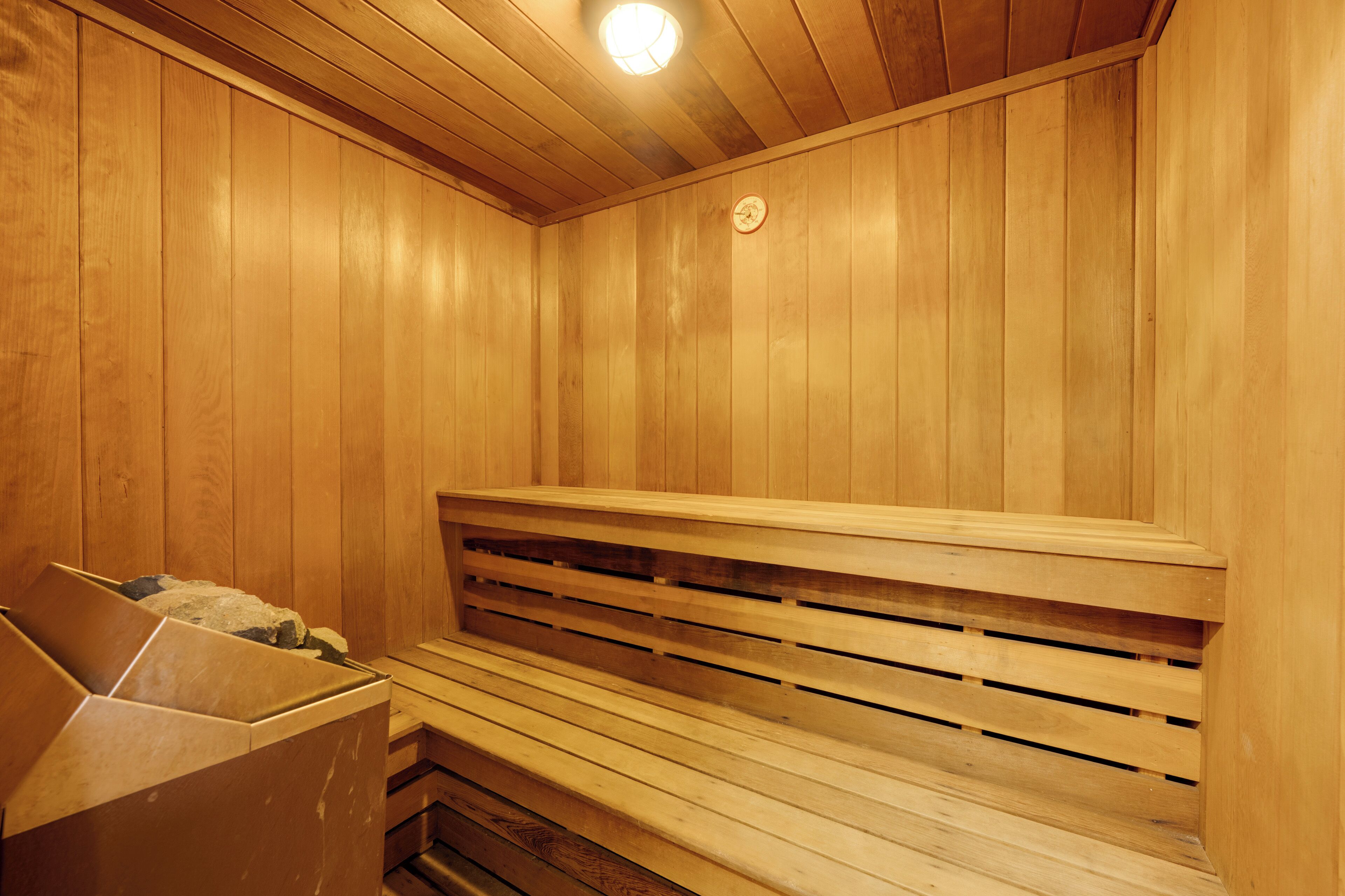 A wooden sauna with benches and a stone container.