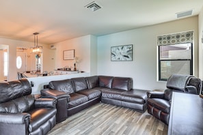 A living room with a sectional sofa, a dining area, and a large window. - Game Room, Pool & Lake Fun at 'indian Land Oasis' (Lake Havasu City)