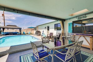 Ein überdachter Außenbereich mit Pool, Sitzgelegenheiten und einer Bar.
