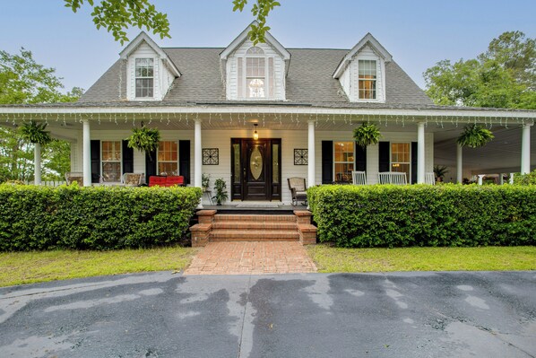 Kaksikerroksinen talo, jossa on kuisti, pääovi ja tiilestä tehty polku, joka johtaa sisäänkäynnille.