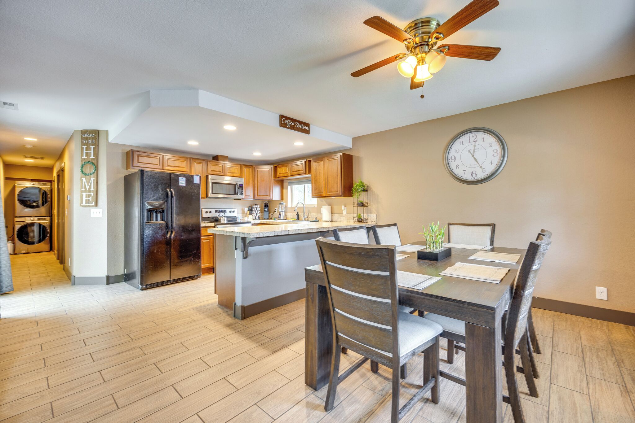 A modern kitchen with a central island, wooden cabinetry, and a ceiling fan.