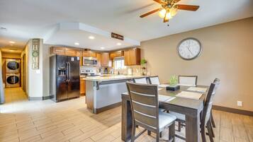 A modern kitchen with a central island, wooden cabinetry, and a ceiling fan.