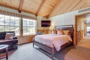 Un dormitorio con techo de madera, una cama, un televisor y una ventana con vistas.