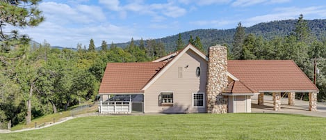 A two-story house with a stone chimney, a red roof, and a covered porch.