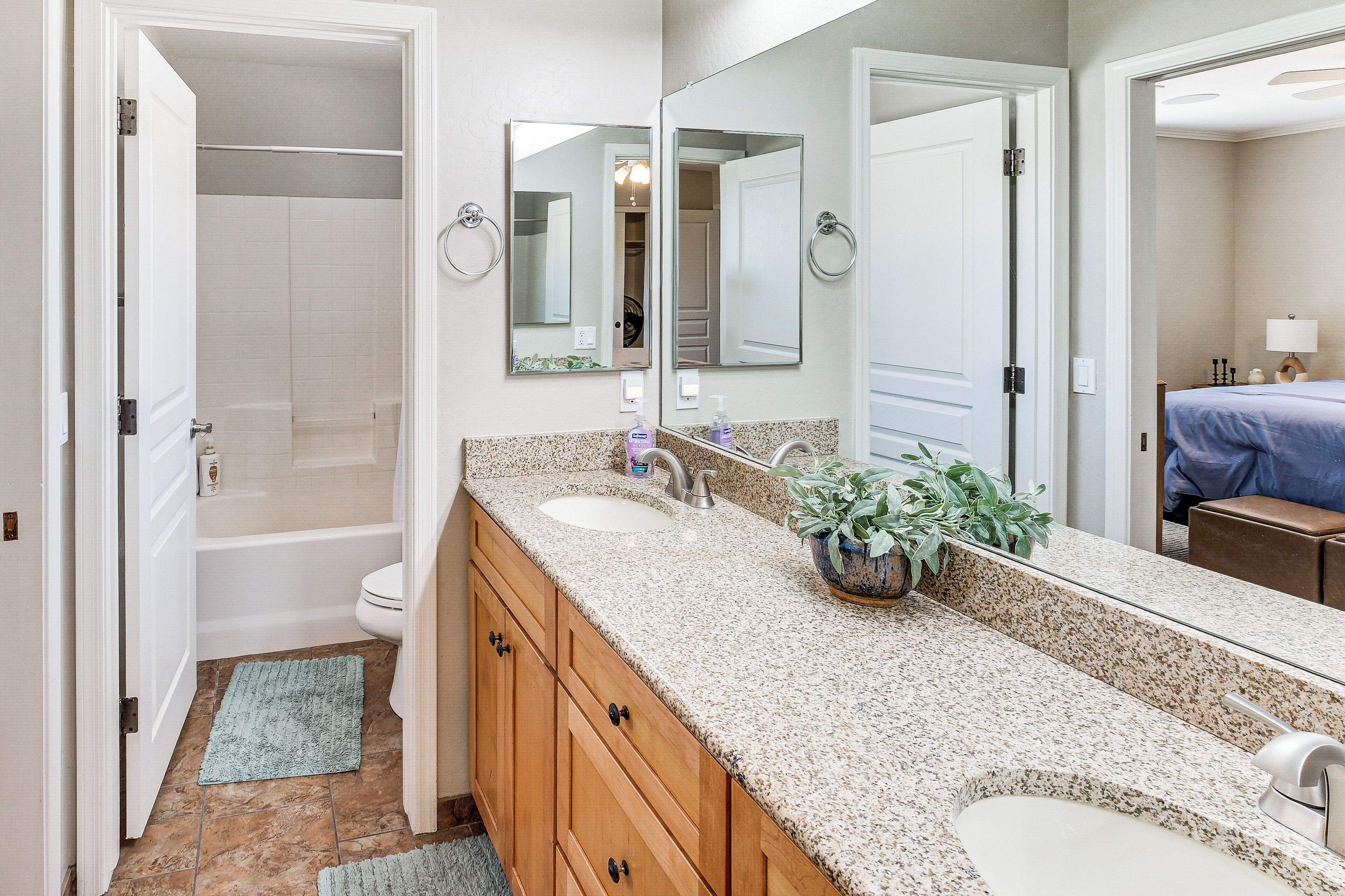 A bathroom with a double sink vanity, a large mirror, a bathtub, and a shower.