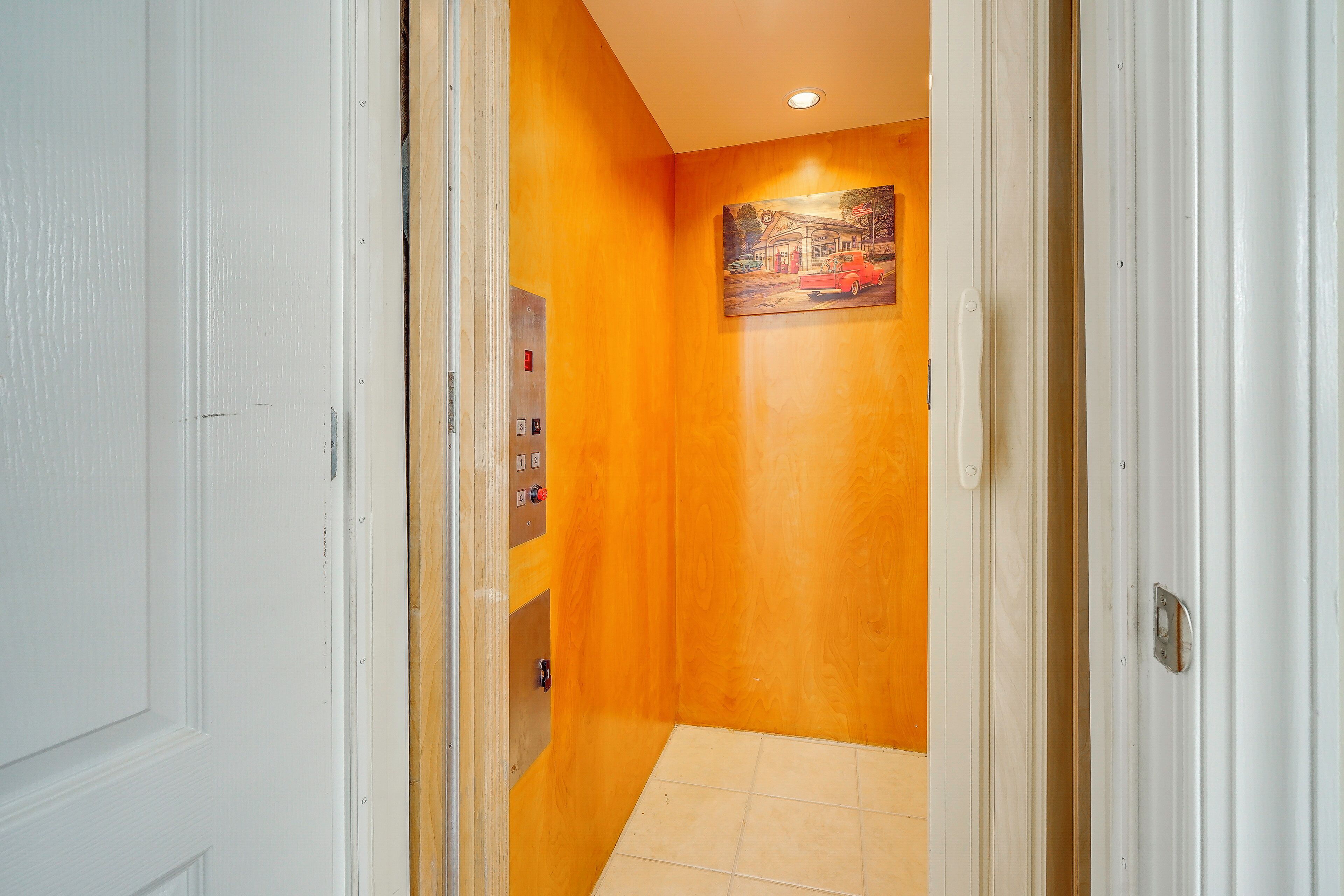Un couloir avec un mur en bois, un tableau et un sol carrelé.