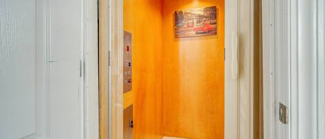 Un couloir avec un mur en bois, un tableau et un sol carrelé.