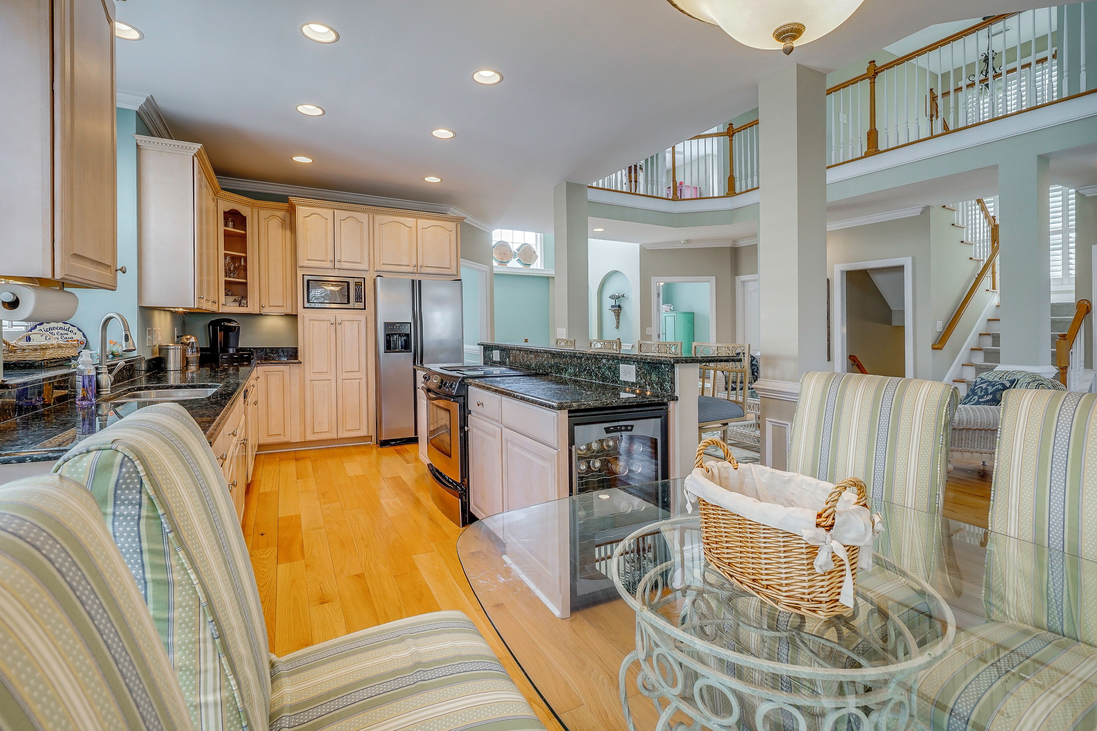 A spacious kitchen with wooden cabinets, a dining area with striped upholstered chairs, and a glass-top table.