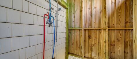 Una habitación de madera con ventana, paredes de azulejos blancos y una ducha con manguera roja.