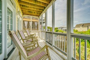 A covered porch with wooden chairs and a railing, overlooking a residential area. - Walk to Beach! Spacious Surf City Escape (Holly Ridge)