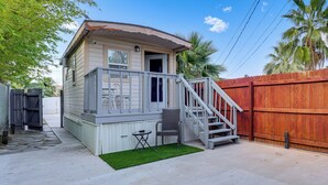 A small house with a porch, a staircase, and a fenced yard. - Tiny House Experience in Las Vegas w/ Free Parking (Las Vegas)