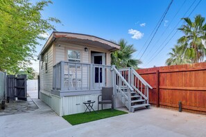 Ein kleines Haus mit Veranda, Treppe und umzäunter Garten.