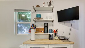 A kitchenette with a coffee maker, a toaster, and a flat-screen TV mounted on the wall. - Tiny House Experience in Las Vegas w/ Free Parking (Las Vegas)