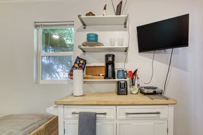 Eine Küchenzeile mit Kaffeemaschine, Toaster und einem flachbildfernseher an der Wand.