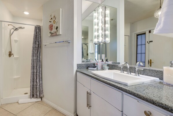 Une salle de bain avec une douche, un meuble-lavabo et un grand miroir.