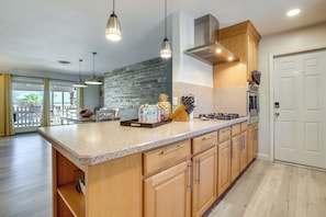 A kitchen with a large island, wooden cabinets, and pendant lighting.