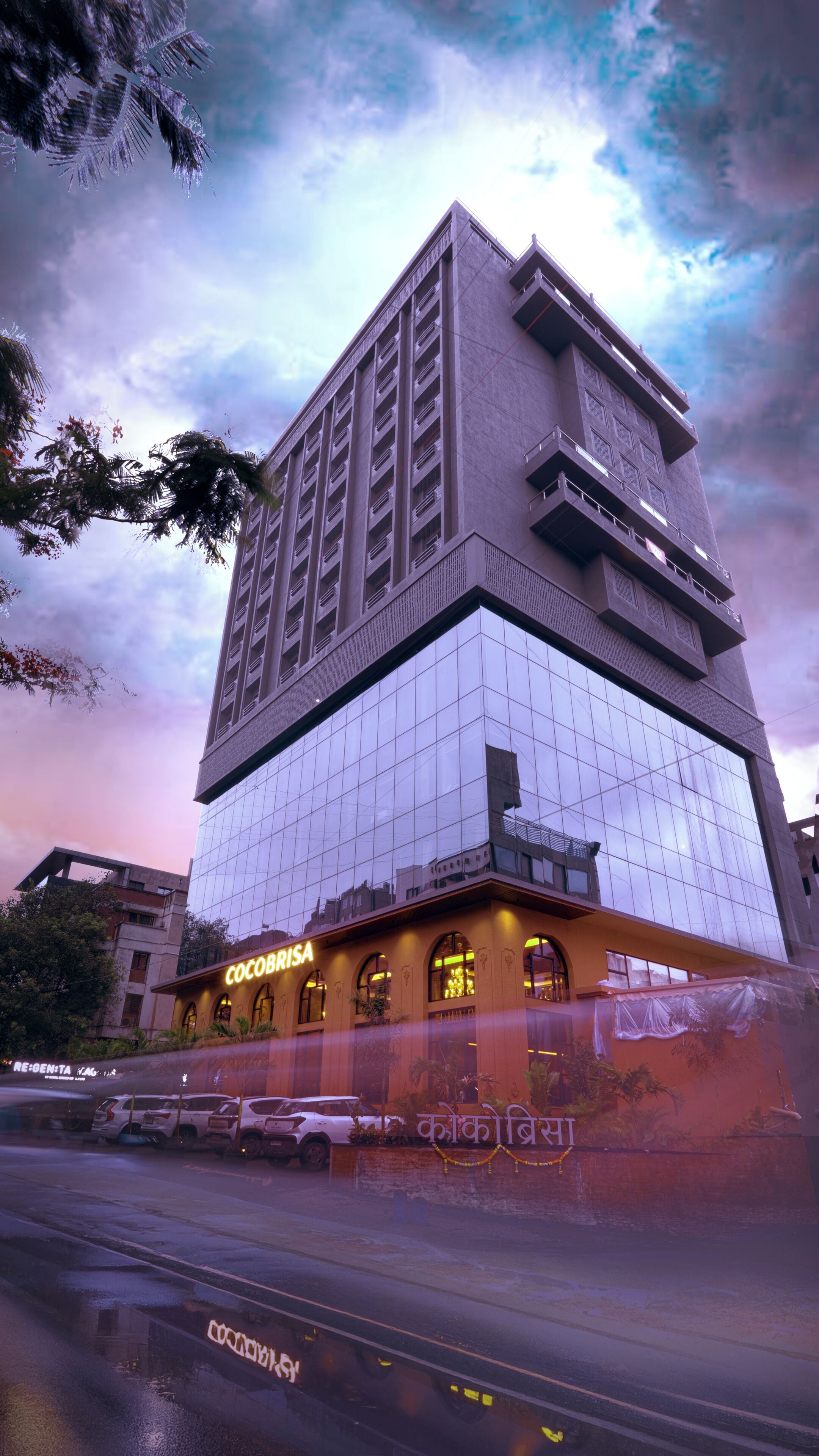 A high-rise hotel with a modern glass facade, multiple balconies, and a ground-level entrance with signage.