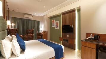 Ein Hotelzimmer mit Bett, Schreibtisch, Fernseher und einer Minibar.