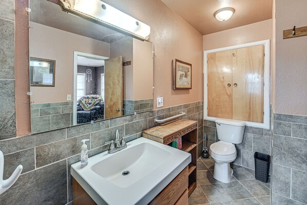 Un baño con un espejo grande, un lavabo, un inodoro y un mueble de tocador con un perchero para toallas.