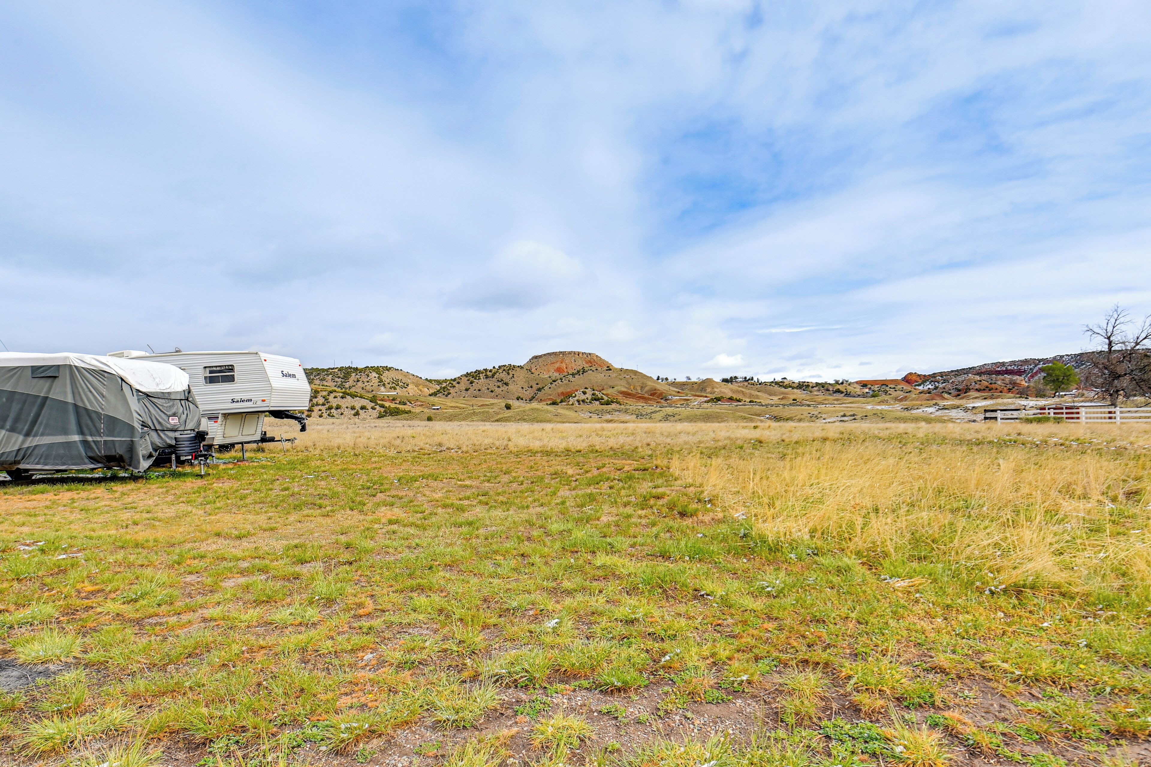 A campsite with two RVs, grassy terrain, and a hill in the background.