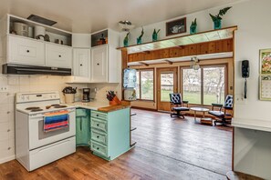 A kitchen with a stove, cabinets, and a dining area with chairs and a table.