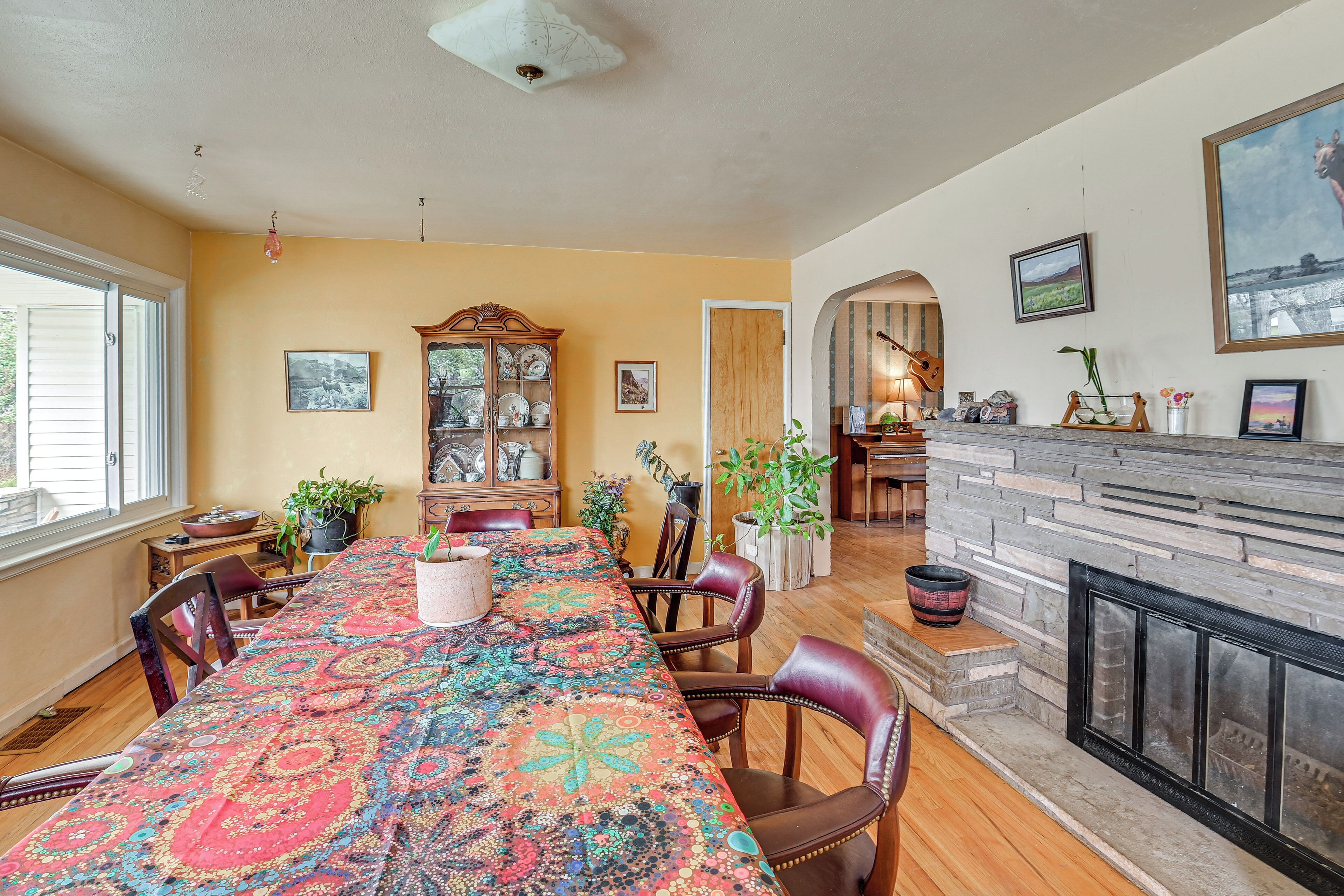 A dining area with a long table, chairs, a fireplace, and various decorative items.