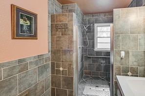 A bathroom with a shower, a sink, and a framed picture on the wall.