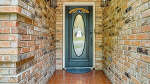 A brick wall with a door featuring a decorative arch and a doormat. - 3 Mi to Six Flags! Family Getaway w/ Outdoor Oasis (Grand Prairie)
