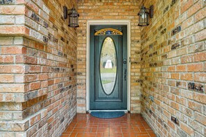 A brick wall with a door featuring a decorative arch and a doormat. - 3 Mi to Six Flags! Family Getaway w/ Outdoor Oasis (Grand Prairie)