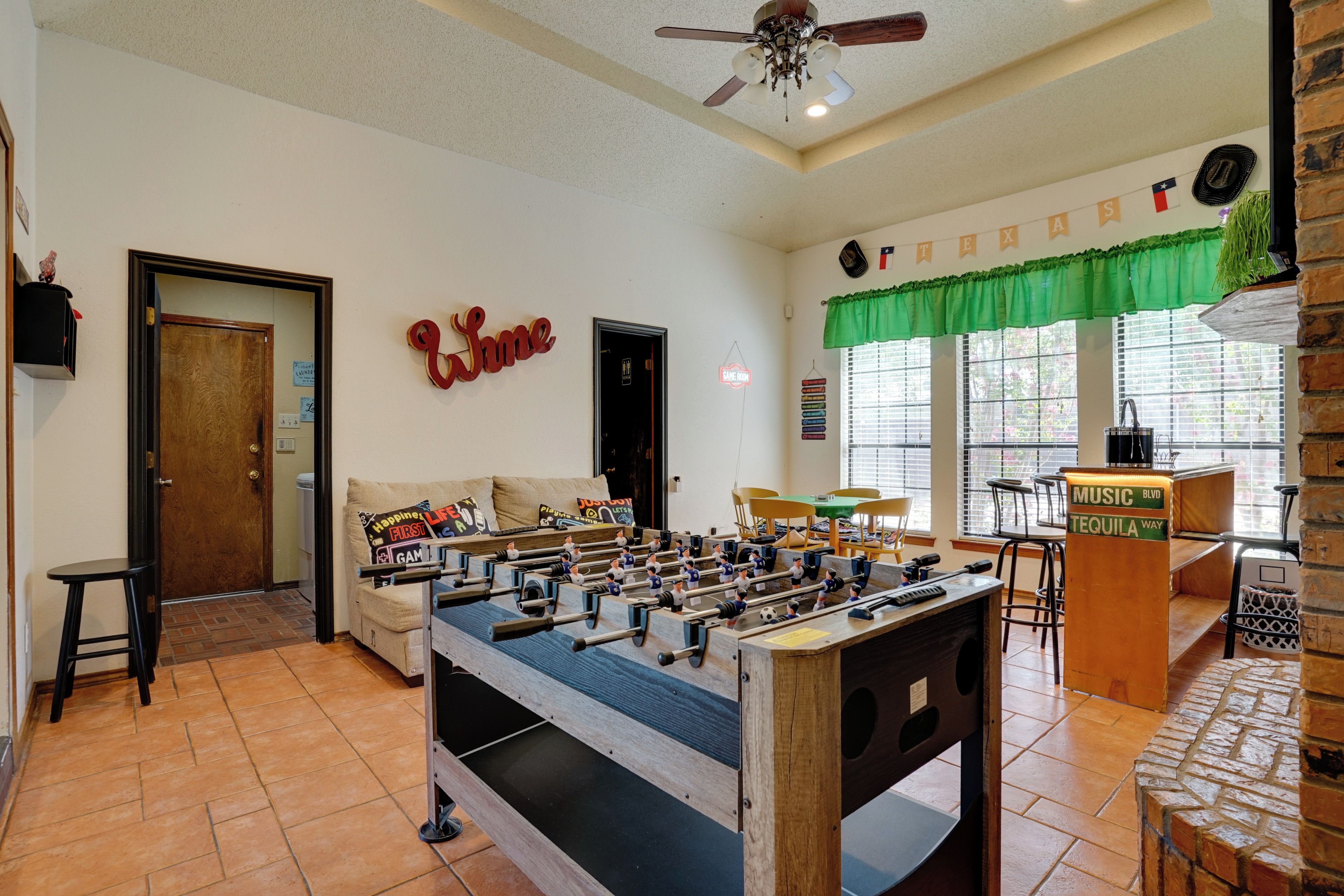 A room with a foosball table, a sofa, a coffee table, and a sign that reads 'Welcome'.