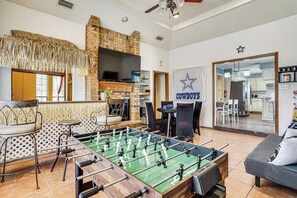 Ein Raum mit Kicker, Fernseher, Kamin und einem Schild mit der Aufschrift 'Cowboys'.