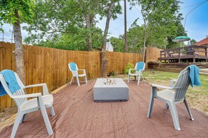 A patio with a fire pit, two chairs, and a covered table. - 3 Mi to Six Flags! Family Getaway w/ Outdoor Oasis (Grand Prairie)