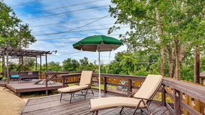A wooden deck with outdoor furniture, including lounge chairs and a table, and a green umbrella. - 3 Mi to Six Flags! Family Getaway w/ Outdoor Oasis (Grand Prairie)