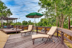 A wooden deck with outdoor furniture, including lounge chairs and a table, and a green umbrella. - 3 Mi to Six Flags! Family Getaway w/ Outdoor Oasis (Grand Prairie)