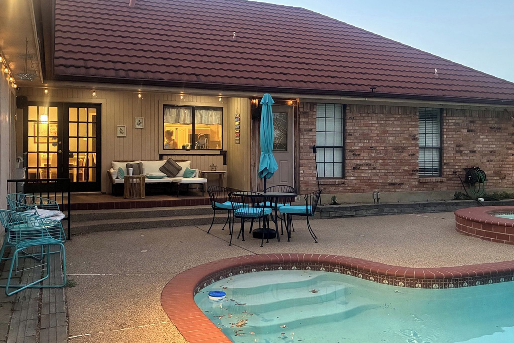 A residential property with a swimming pool, outdoor seating area, and a brick exterior.