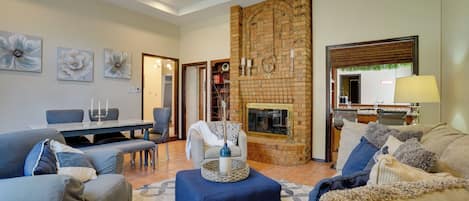 A living room with a fireplace, seating area, and a dining table.
