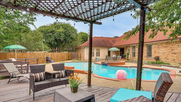 A backyard with a wooden deck, outdoor furniture, a swimming pool, and a pergola. - 3 Mi to Six Flags! Family Getaway w/ Outdoor Oasis (Grand Prairie)